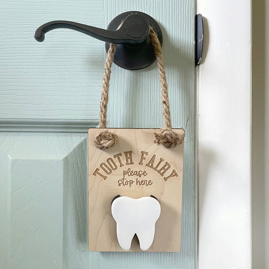 tooth fairy door hanger is hanging on a door and made of wood laser engraved with tooth fairy stop here has a section for a child to insert a tooth and for the tooth fairy to insert money